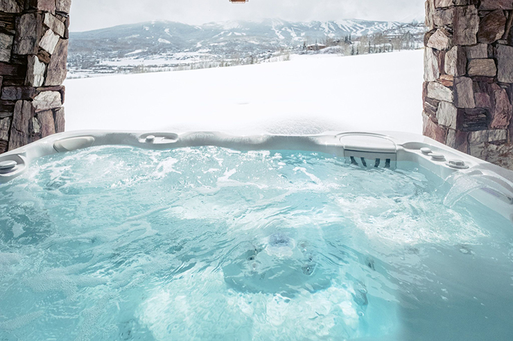 A Caldera Spa looking out into a beautiful view of an open backyard covered in snow