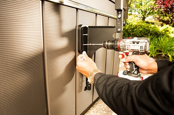 A man drills holes in the side of his hot tub in order to install a hot tub cover lifter