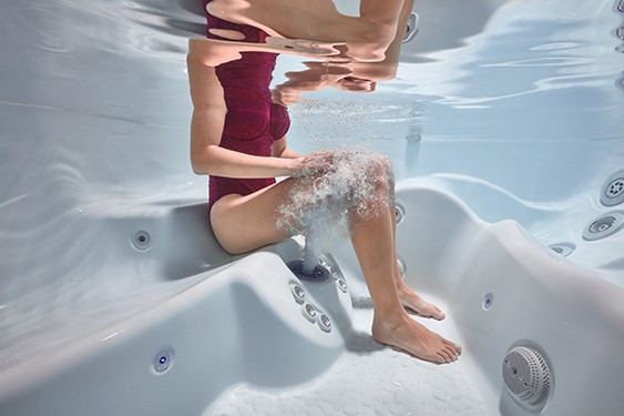 A lady enjoys the targeted massage jet of a hot tub