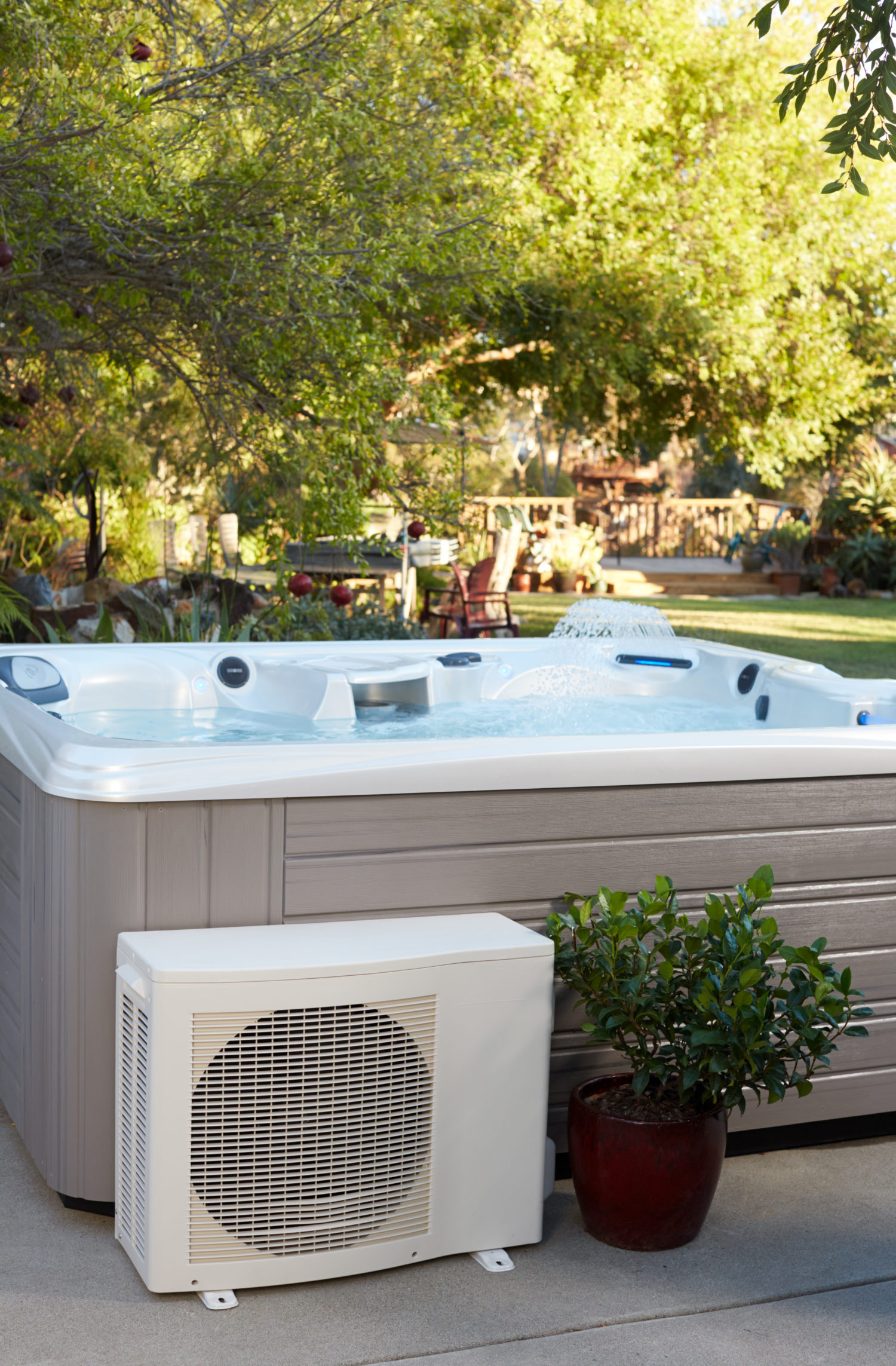 A modern hot tub equipped with CoolZone technology is set in a lush outdoor garden.