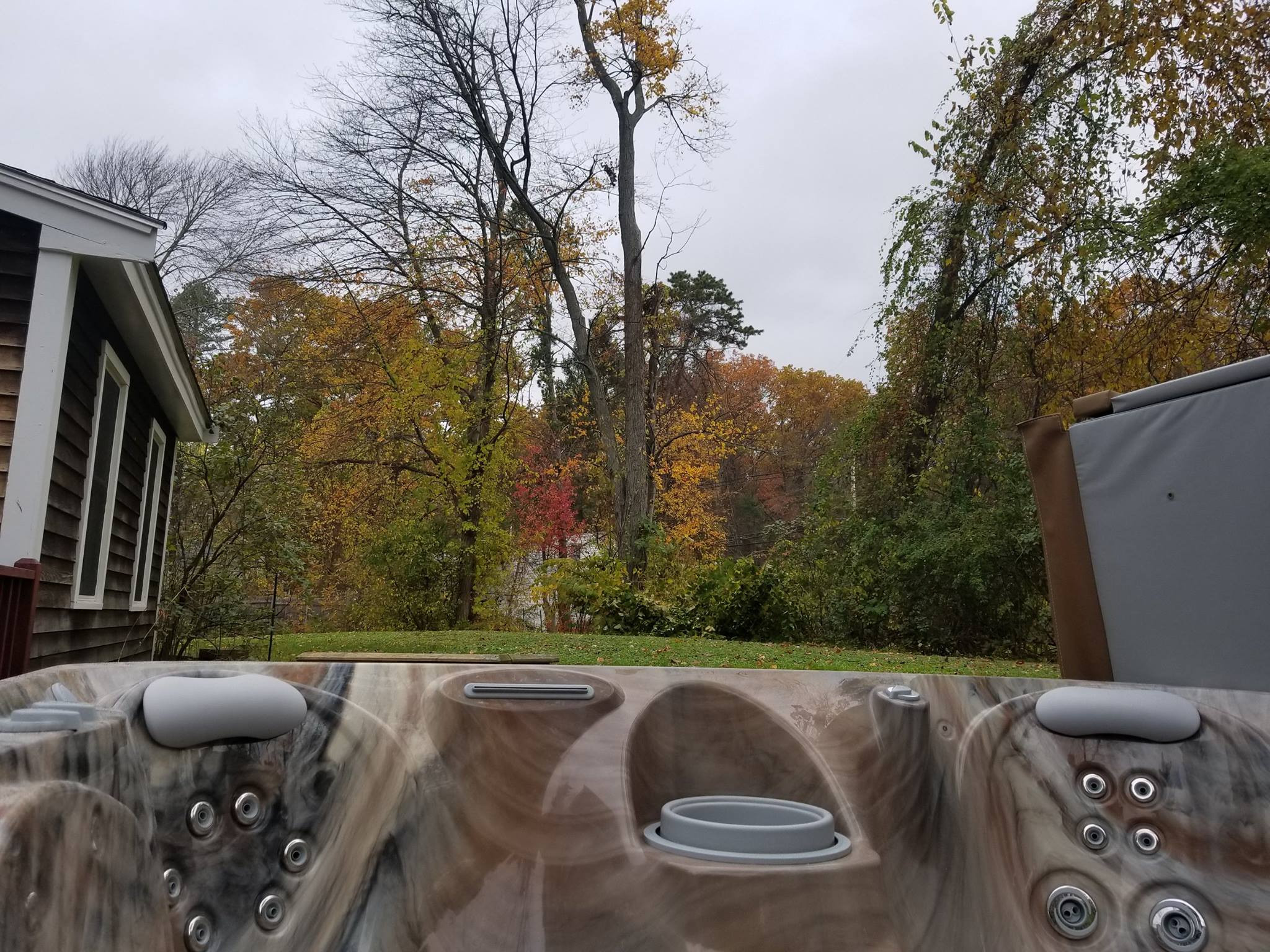 A Caldera spa hot tub in a backyard with colorful fall foliage. Preparing your Caldera Spa for winter ensures it's ready to enjoy when the snow falls.