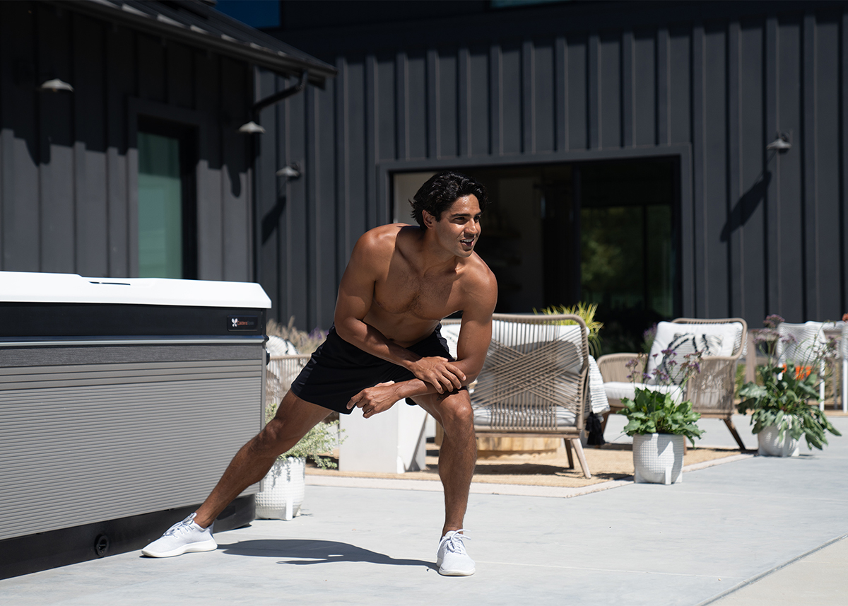 A man working out in an outdoor setting near a Caldera Spas' Utopia Hot Tub.