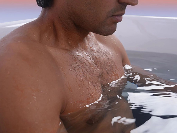 Man immersed in a cold plunge, with water droplets on his chest and shoulders.