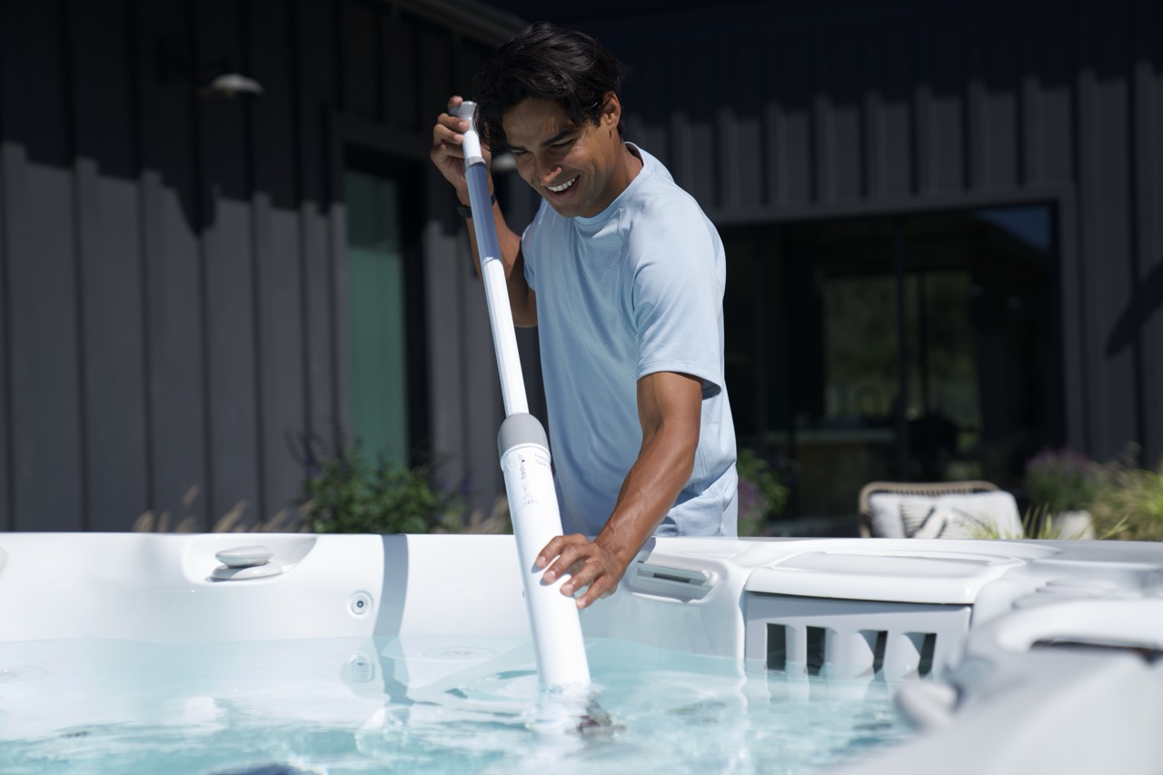 Hot tub owner using a spa vacuum to clean the bottom of a Caldera spa